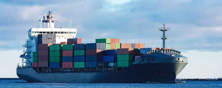 Modern grey container ship moving in still waterの写真素材