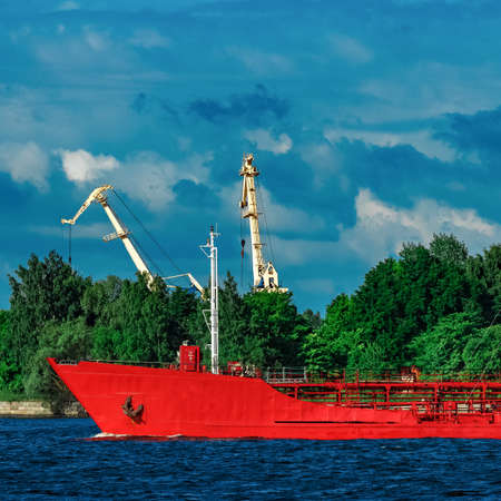 Red cargo tanker ship moving by the riverの写真素材