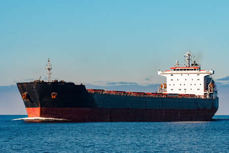 Black cargo ship moving in still Baltic sea water. Riga, Europeの写真素材