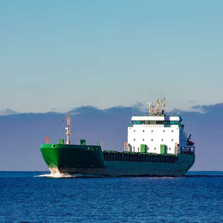 Green cargo ship moving in still water of Baltic seaの写真素材