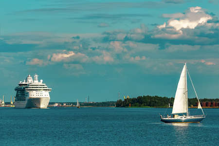Blue sailboat traveling against the cruise liner in Rigaの写真素材