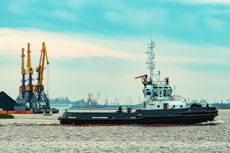 Black tug ship moving to the cargo terminal. Industrial serviceの写真素材