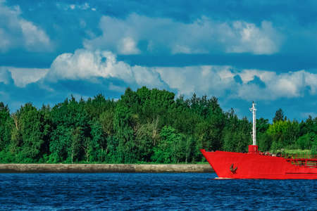 Red cargo tanker ship moving by the riverの写真素材