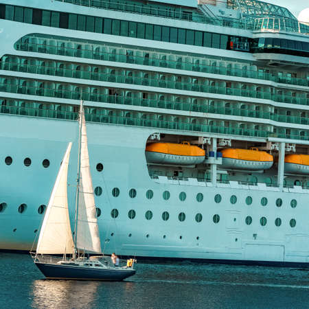 Blue sailboat traveling against the cruise liner in Rigaの写真素材