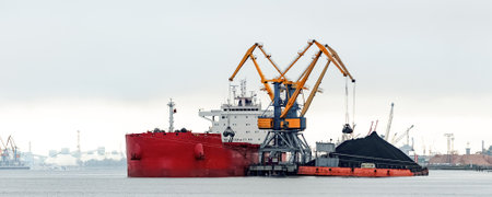 Large red cargo ship loading with a coal in the portの写真素材