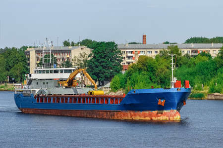 Blue cargo ship with long reach excavator moving to the portの写真素材