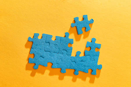 Top View of a Blue Puzzle Peaces Lie on the Yellow Backgroundの写真素材