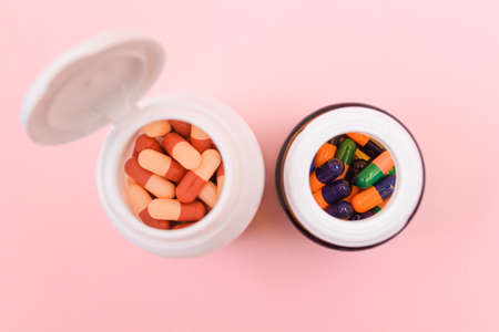 Global Pharmaceutical Industry and Medicinal Products - Different Colored Pills, Tablets and Capsules in Bottle Lying on Pink Background. Copy Space, Top View, Flat Layの写真素材