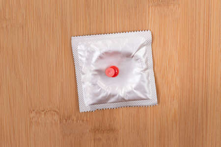 A Joke on Colleagues, Freebie or a Defective Condom - Packaged Latex Condom Pinned to a Wooden Message Boardの写真素材