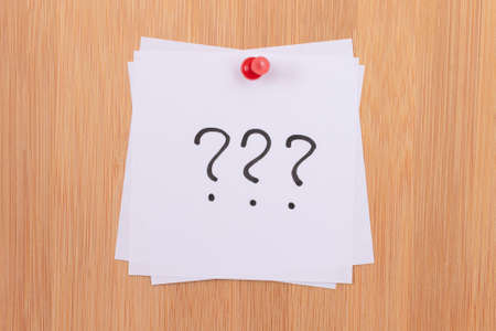 White Sticky Notes with Three Question Marks Pinned to the Wooden Message Board. To Do List Reminder in the Office. Memo Note at Workの写真素材