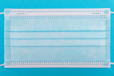 Blue Medical Mask on Blue Background - Top View, Flat Layの写真素材