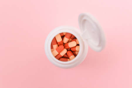 Global Pharmaceutical Industry and Medicinal Products - Different Colored Pills, Tablets and Capsules in Bottle Lying on Pink Background. Copy Space, Top View, Flat Layの写真素材