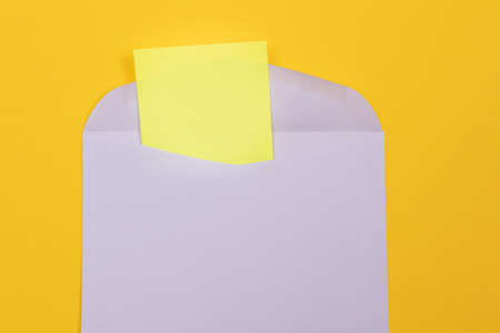Violet Envelope with Blank Yellow Sheet of Paper Inside, Lying on Yellow Background - Mock Up with Copy Space. Receiving Mail or Notice, Sending Postcard - Top View, Flat Layの写真素材