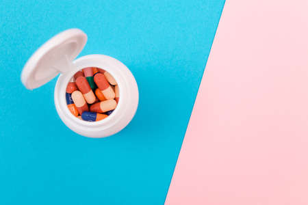 Global Pharmaceutical Industry and Medicinal Products - Different Colored Pills, Tablets and Capsules in Bottle Lying on Split Blue and Pink Background, Top View, Flat Layの写真素材