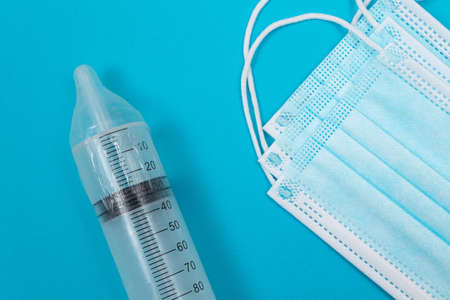 Safe Vaccine, Anti Vaccination Concept - Syringe in a Condom Lay on Blue Table in Clinic or Hospital. Mistrust of Vaccination. Natural Immunity. Skepticism About the Vaccine. Freedom and Human Rightsの写真素材