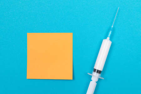 Vaccination, Immunology or Revaccination Concept - A Medical Disposable Syringe Lying on Blue Table...