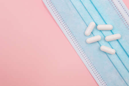 White Pills or Tablets on Medical Face Mask, Lying on Pink Background. Pharmaceutical Industry and Medicinal Productsの写真素材