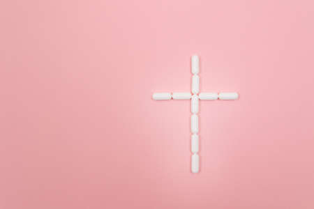 Pharma Harm. A Grave Cross Made from White Pills, Lying on Pink Background. Global Pharmaceutical Industry and Medicinal Productsの写真素材