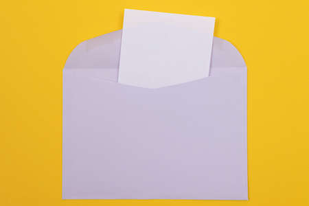 Violet Envelope with Blank White Sheet of Paper Inside, Lying on Yellow Background - Mock Up with Copy Space. Receiving Mail or Notice, Sending Postcard - Top View, Flat Layの写真素材