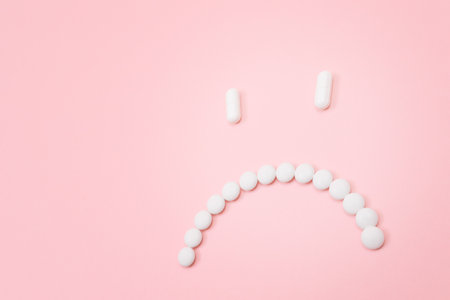 Pharma Harm. Sad Smiley Face Made from White Pills, Lying on Pink Backgrond. Global Pharmaceutical Industry and Medicinal Productsの写真素材