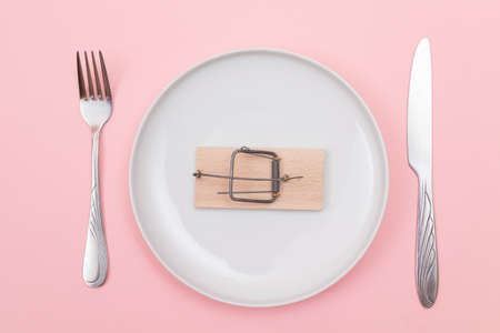 Wooden Mouse Trap on White Ceramic Plate with Fork and Knife Lying on Blue Background - Top View, Flat Layの写真素材