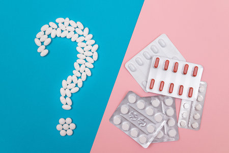 Question Mark Made from White Pills and Tablets with Pill Packages, Lying on Split Blue and Pink...