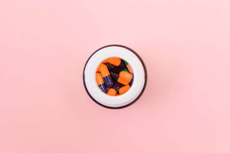 Global Pharmaceutical Industry and Medicinal Products - Different Colored Pills, Tablets and Capsules in Bottle Lying on Pink Background. Copy Space, Top View, Flat Layの写真素材