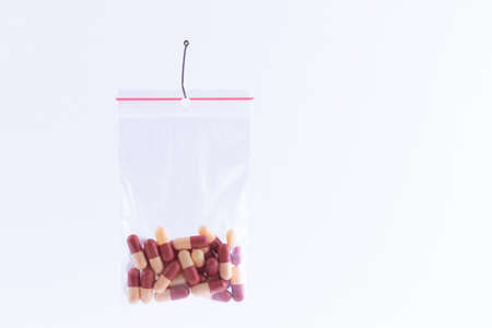 The Pharmaceutical Trap and Drug Addiction - Colored Pills or Tablets Hanging in Small Ziplock Bag...