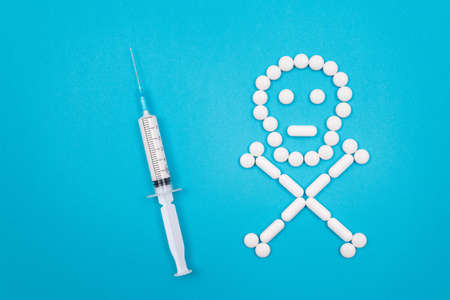 Dangerous Pharmaceutical Products or Unsafe Pills and Tablets - Skull or Death Symbol Made from White Pills Lying on Blue Backgroundの写真素材