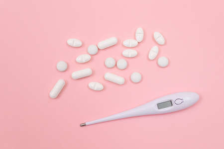 White Pills or Tablets with Electronic Thermometer on Pink Background. Pharmaceutical Industry and Medicinal Productsの写真素材