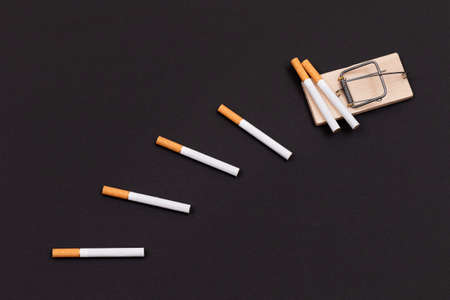 Tobacco Addiction and the World Corporations Trap - Cigarettes in Wooden Mousetrap on Black Backgroundの写真素材