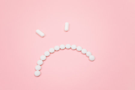 Pharma Harm. Angry Smiley Face Made from White Pills, Lying on Pink Backgrond. Global Pharmaceutical Industry and Medicinal Productsの写真素材