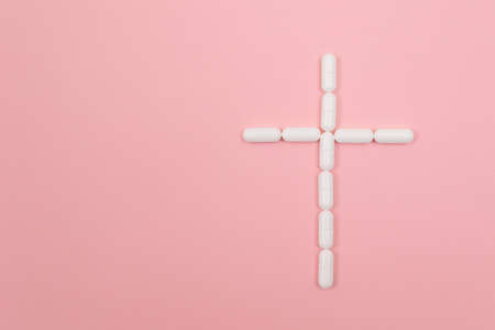 Pharma Harm. A Grave Cross Made from White Pills, Lying on Pink Background. Global Pharmaceutical Industry and Medicinal Productsの写真素材