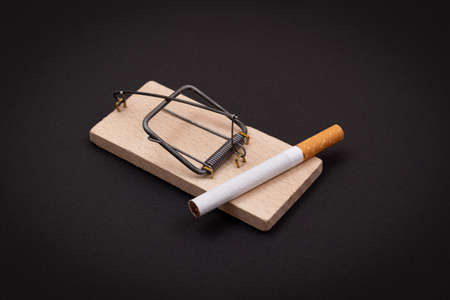 Tobacco Addiction and the World Corporations Trap - Cigarettes in Wooden Mousetrap on Black Backgroundの写真素材