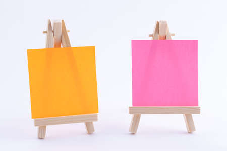Two Wooden Easels Miniature with Blank Colored Square Canvas or Memo Paper - Mockup. Mini Wooden Stand with Clean Artboard on White Background, Copy Spaceの写真素材