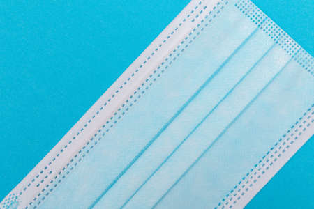Blue Medical Mask on Blue Background - Top View, Flat Layの写真素材