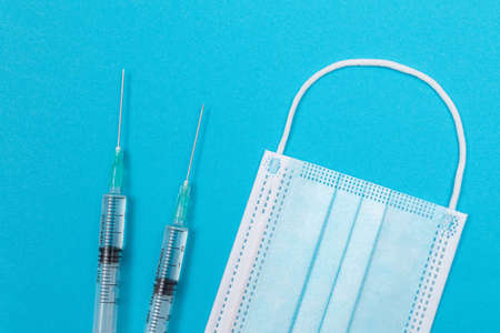 Several Syringe and Face Mask on Blue Table - Top View. Syringes are Prepared for Vaccination or...