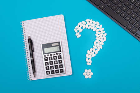 Treatment Costs and Budget. Question Mark Made from White Pills and Tablets with Calculator and Notepad, Lying on Blue Background. Global Pharmaceutical Industry and Medicinal Productsの写真素材