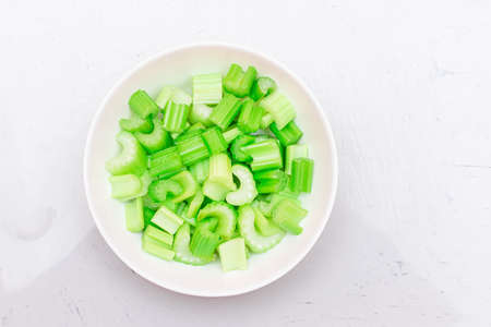Fresh Chopped Celery Slices with Water Drops on White Dish - Top View. Vegan and Vegetarian Culture. Raw Food. Healthy Diet with Negative Calorie Contentの写真素材