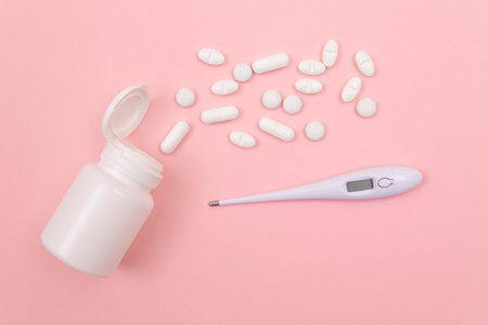 White Pills or Tablets with Electronic Thermometer on Pink Background. Pharmaceutical Industry and Medicinal Productsの写真素材