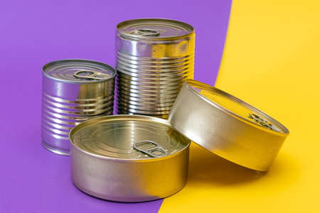 A Group of Stacked Tin Cans with Blank Edges on Split Yellow and Violet Background. Canned Food....