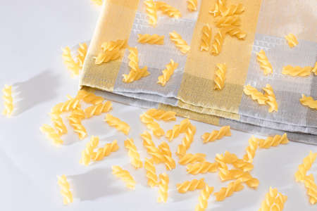Uncooked Fusilli Pasta Scattered on White Table. Raw and Dry Macaroni. Fat and Unhealthy Foodの写真素材