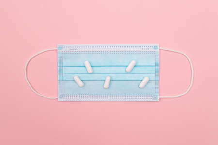 White Pills or Tablets on Medical Face Mask, Lying on Pink Background. Pharmaceutical Industry and Medicinal Productsの写真素材