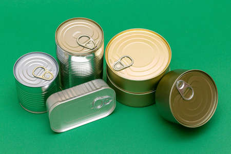 A Group of Stacked Tin Cans with Blank Edges on Green Background. Canned Food. Different Aluminum Cans for Safe and Long Term Storage of Food. Steel Sealed Food Storage Containersの写真素材