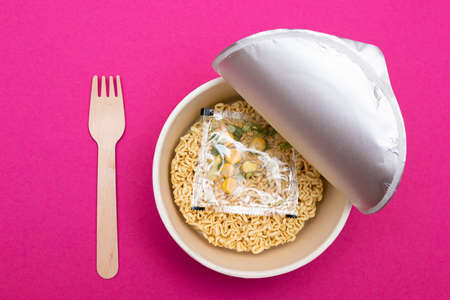 Opened Package with Uncooked Instant Noodles on Pink Background. Raw Pasta. Dry Asian Fast Food. Quick Lunchの写真素材