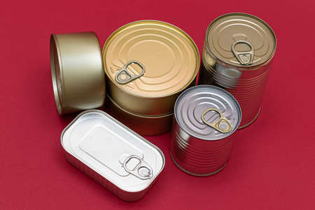 A Group of Stacked Tin Cans with Blank Edges on Red Background. Canned Food. Different Aluminum Cans for Safe and Long Term Storage of Food. Steel Sealed Food Storage Containersの写真素材