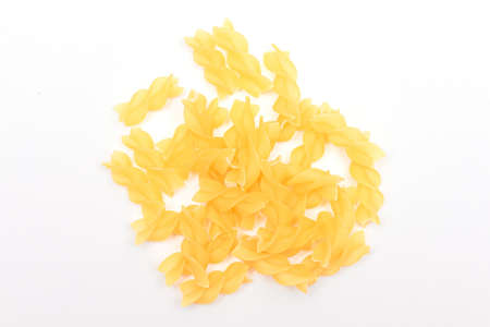 A Heap of Uncooked Fusilli Pasta Scattered on White Table. Raw and Dry Macaroni. Unhealthy and Fat Food. Italian Cultureの写真素材