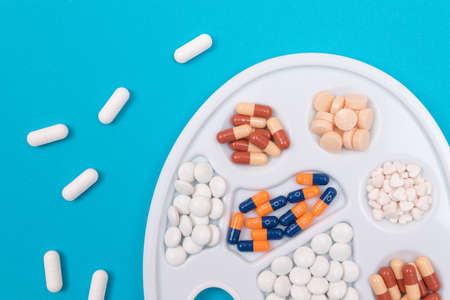 Global Pharmaceutical Industry and Medicinal Products - Different Colored Pills, Tablets and Capsules on White Art Palette Lying on Blue Background, Flat Layの写真素材