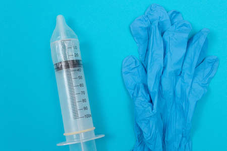 Safe Vaccine, Anti Vaccination Concept - Syringe in a Condom Lay on Blue Table in Clinic or Hospital. Mistrust of Vaccination. Natural Immunity. Skepticism About the Vaccine. Freedom and Human Rightsの写真素材