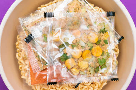 Opened Package with Uncooked Instant Noodles on Violet Background. Raw Pasta. Dry Asian Fast Food. Quick Lunchの写真素材